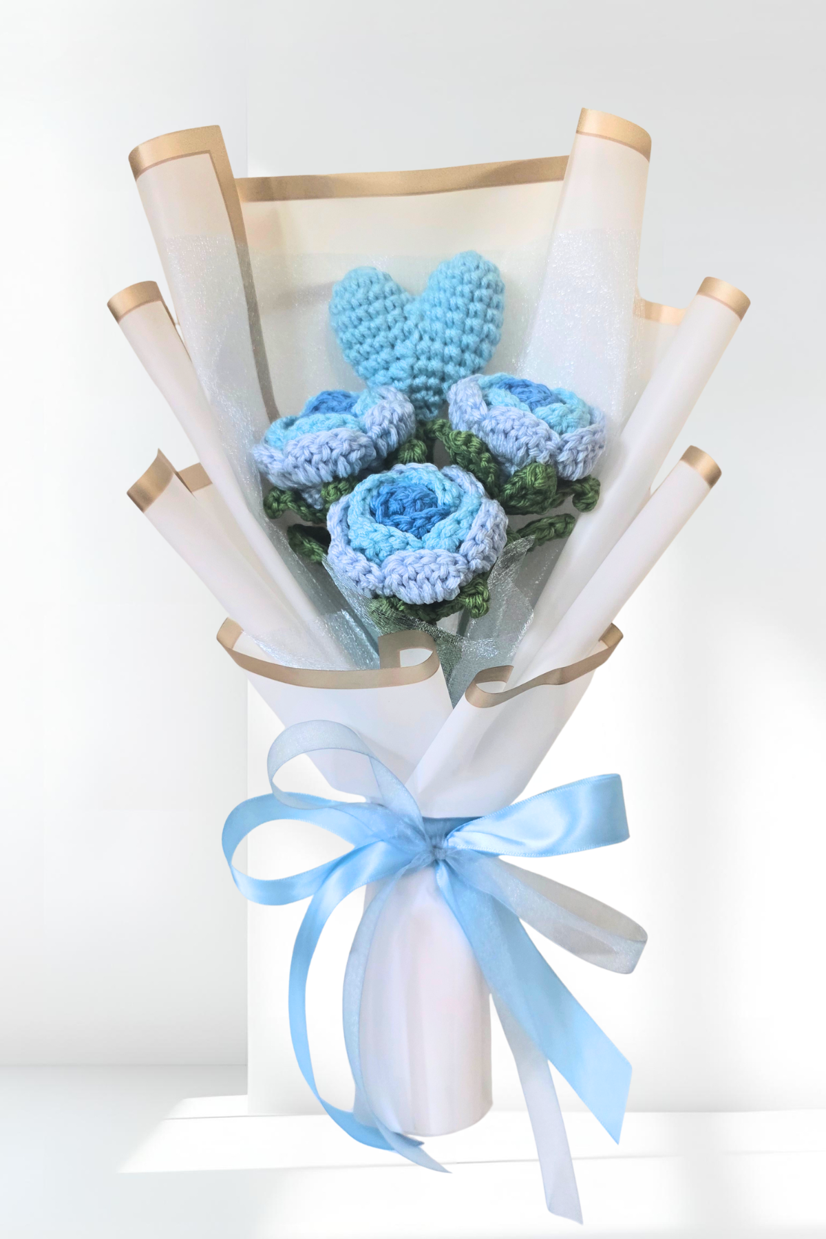 Bouquet of blue flowers wrapped in white paper with a blue ribbon on a light gray background