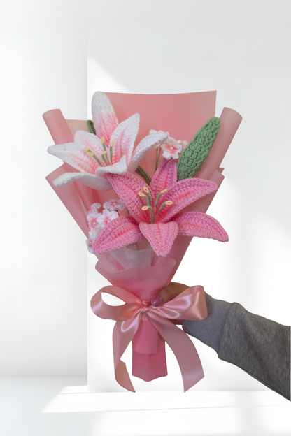 Bouquet of pink lily flowers with a pink ribbon held by a hand against a white background