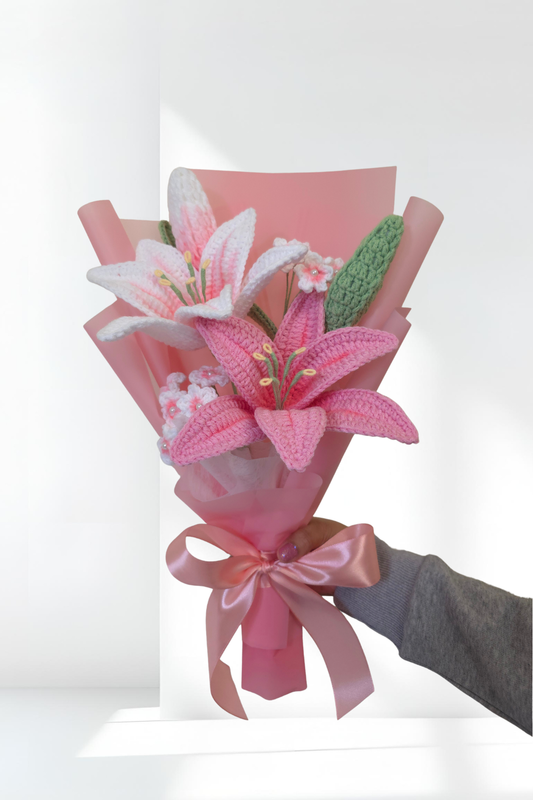 Bouquet of pink lily flowers with a pink ribbon held by a hand against a white background