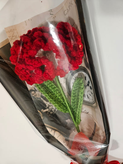 Handcrafted crochet red carnation flower with green leaves, wrapped in black and tied with a satin ribbon for a charming, delicate look.