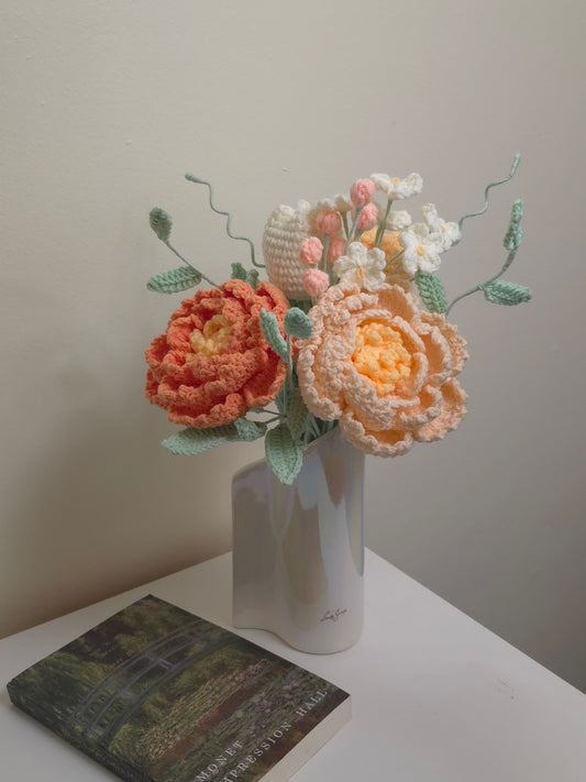 Crocheted peony and tulip flowers on a white vase