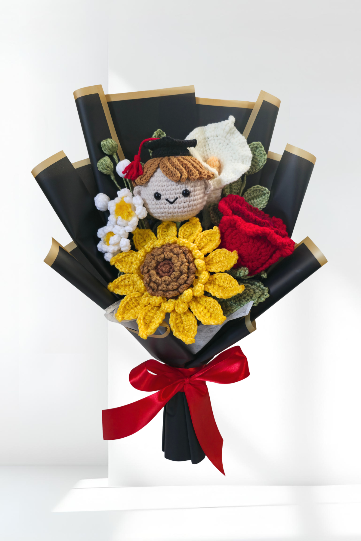Graduation bouquet made of crochet flowers, and a small figurine on a white background