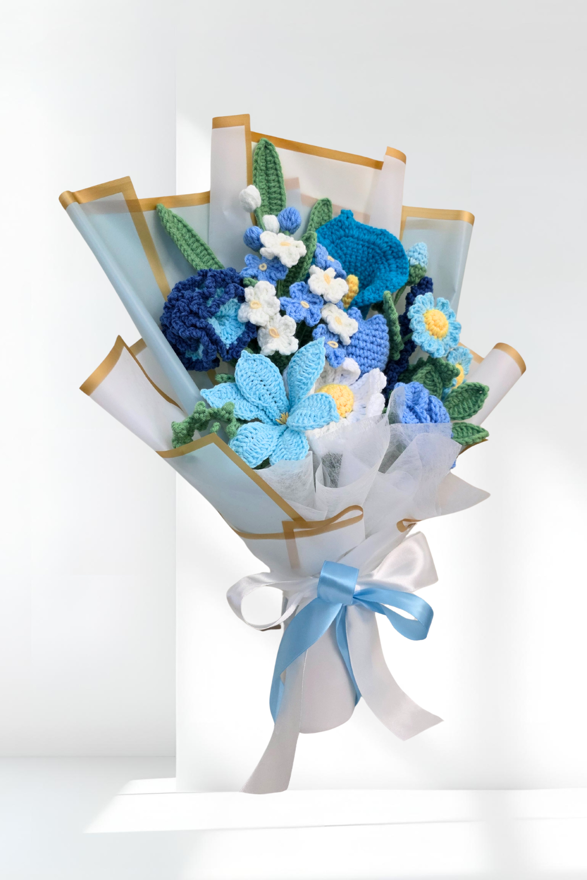 Bouquet of blue and white flowers wrapped in paper with a ribbon on a white background