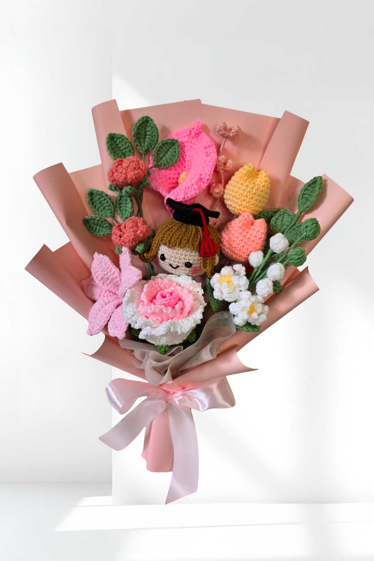Bouquet of knitted flowers and a small doll on a white background