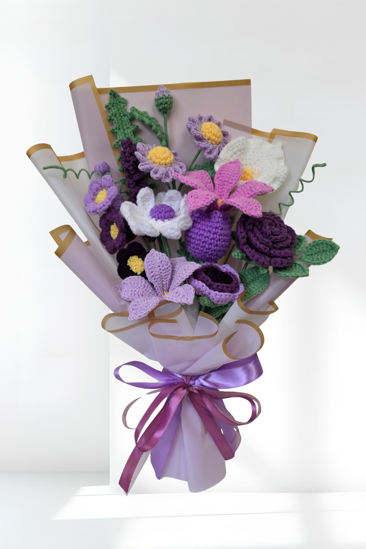 Bouquet of crochet flowers with a purple ribbon on a white background