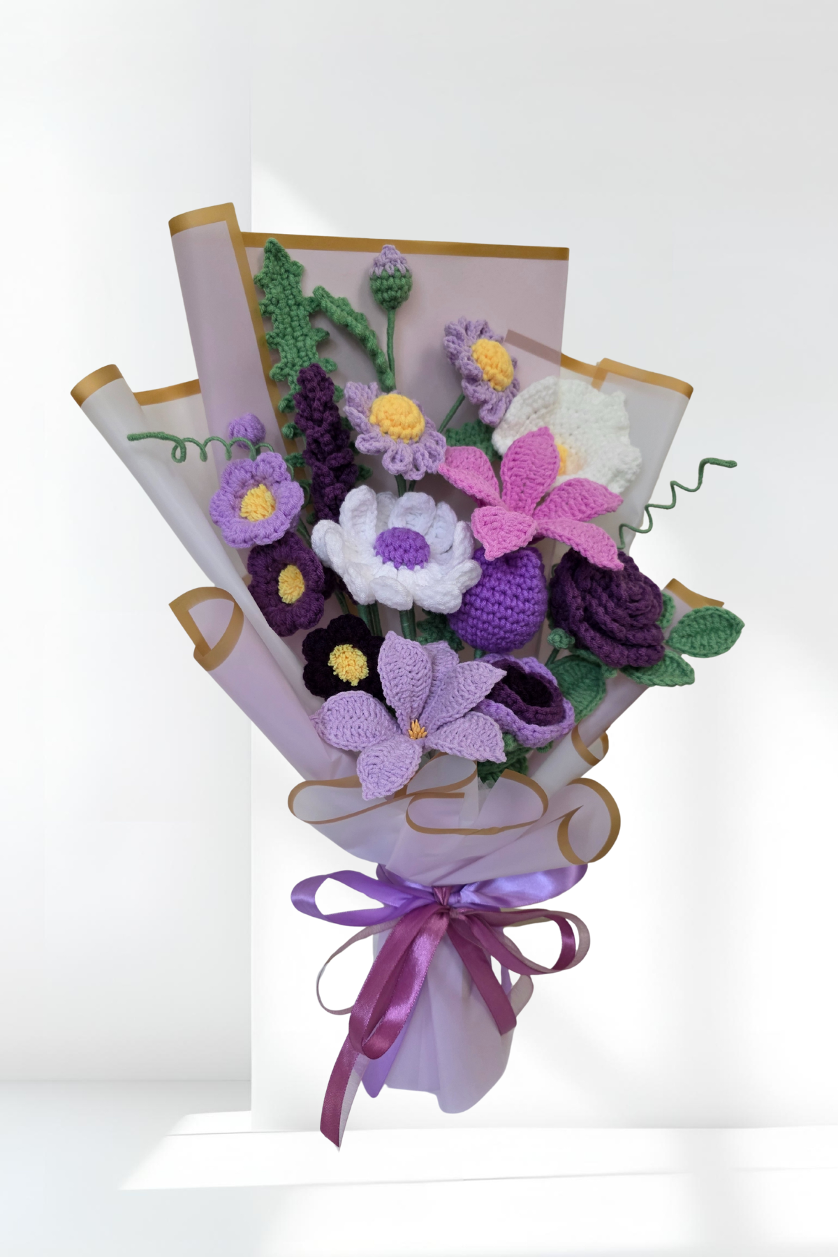Knitted crochet flower bouquet with purple and white flowers on a white background