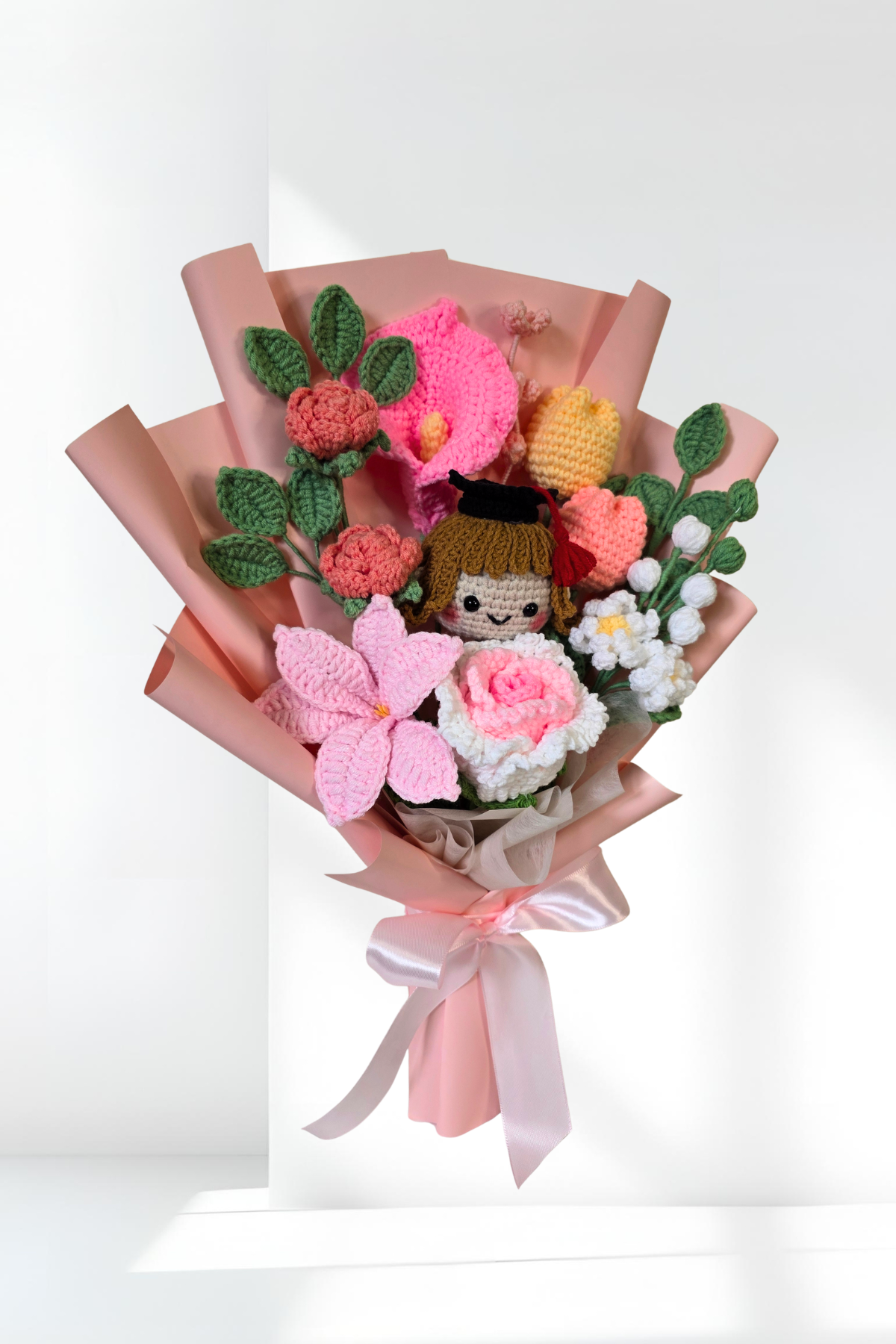 Bouquet of knitted flowers with a small knitted doll in the center on a white background