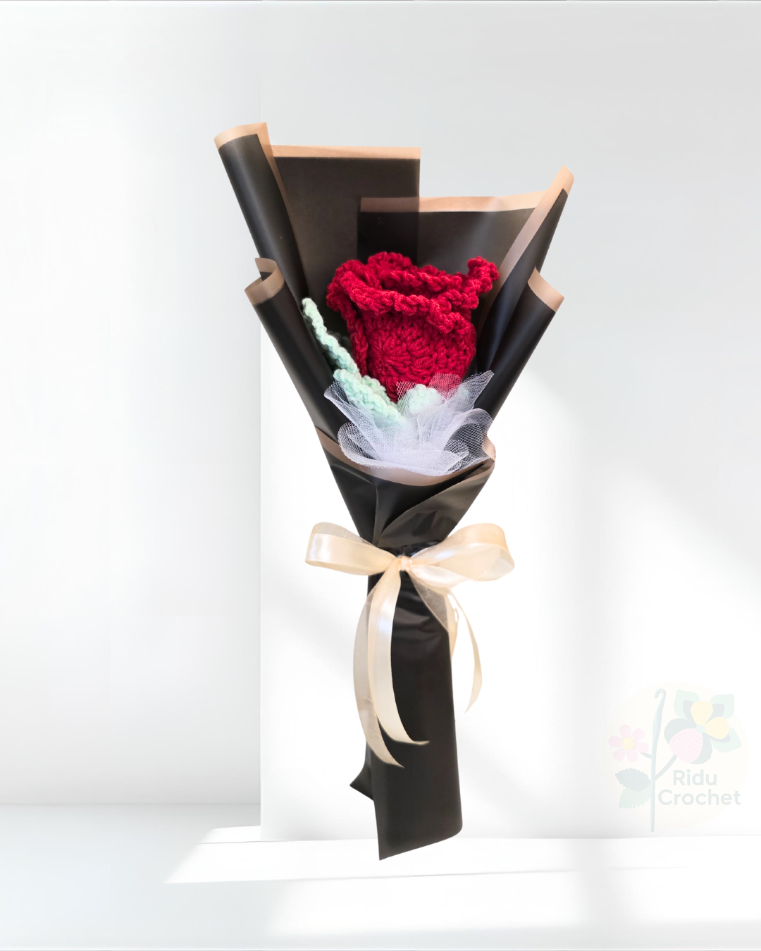 Bouquet of crocheted rose flower wrapped in black paper with a bow on a white background
