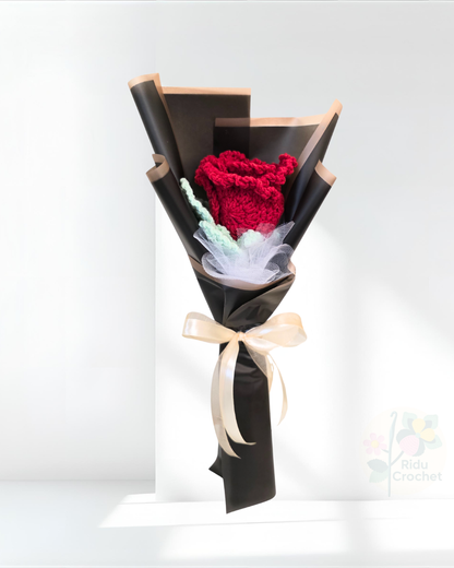 Bouquet of crocheted rose flower wrapped in black paper with a bow on a white background