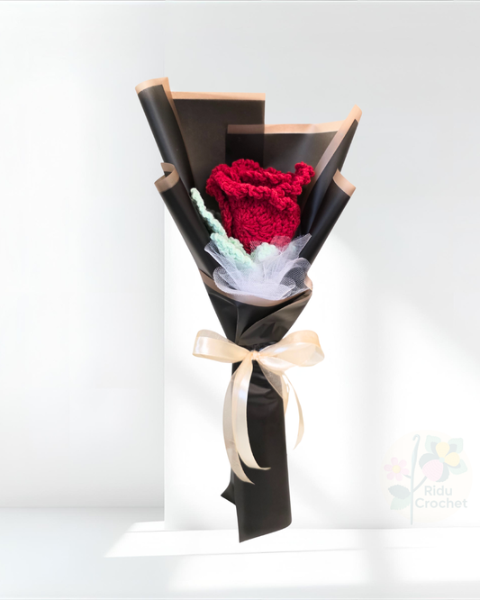 Bouquet of crocheted rose flower wrapped in black paper with a bow on a white background
