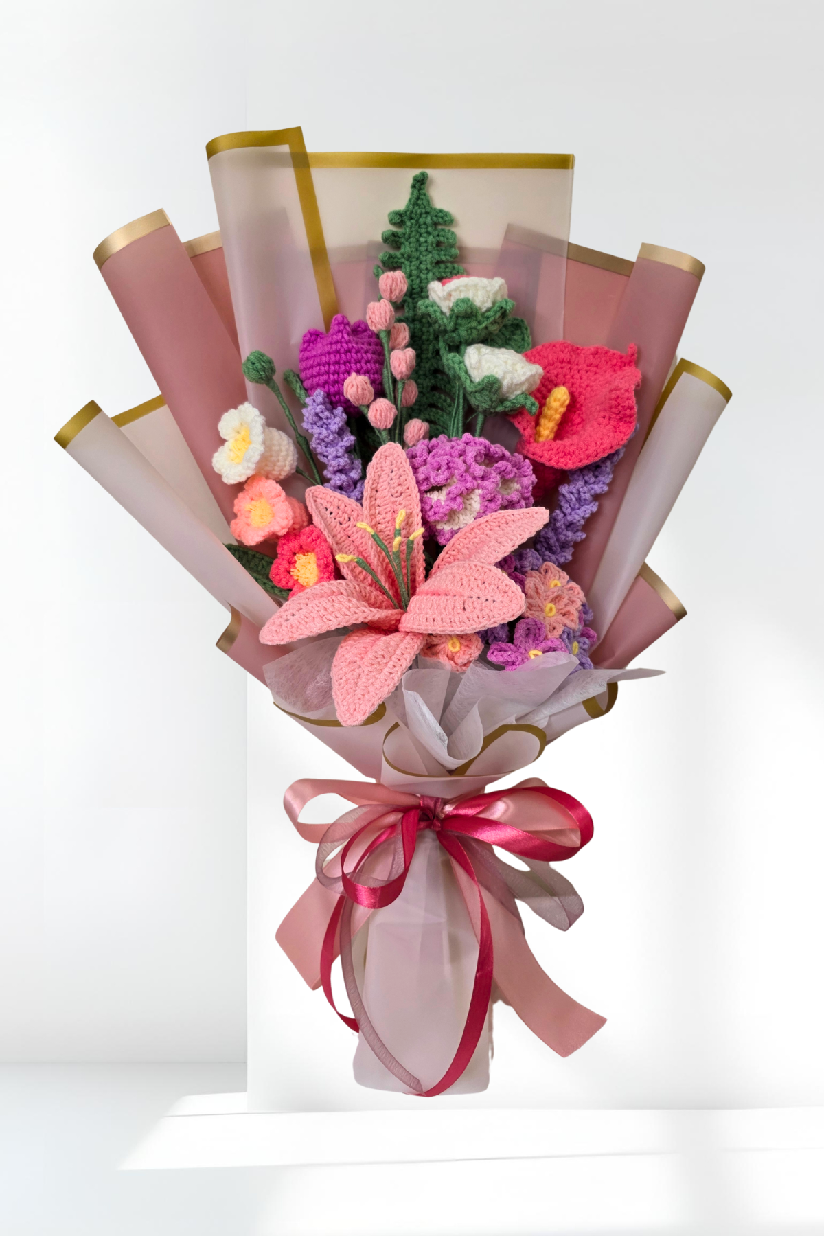Bouquet of knitted flowers with a pink ribbon on a white background