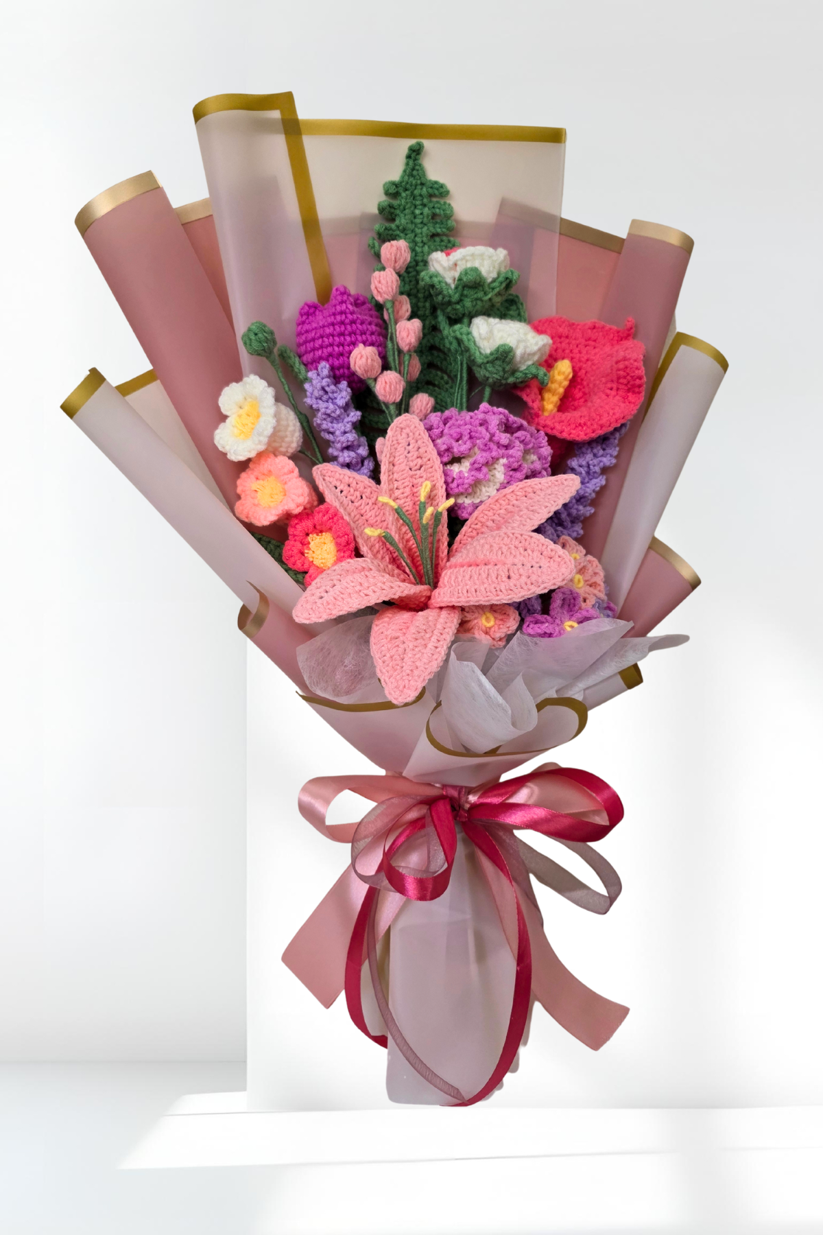 Bouquet of knitted flowers with a pink ribbon on a white background