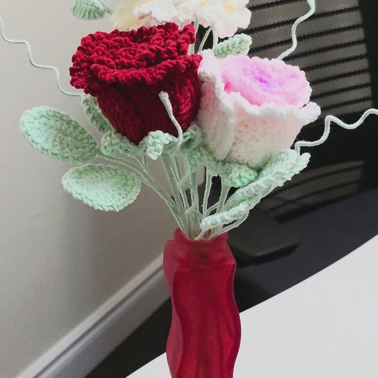Decorative flower arrangement in a red vase on a white surface with a light gray background