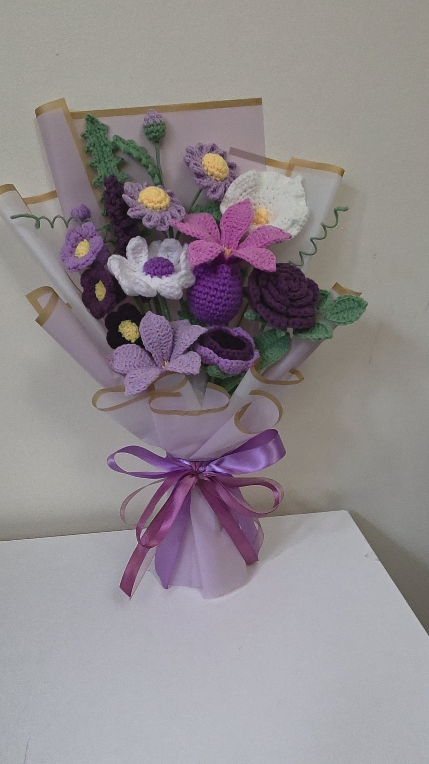 crochet flower bouquet with a purple ribbon on a white background