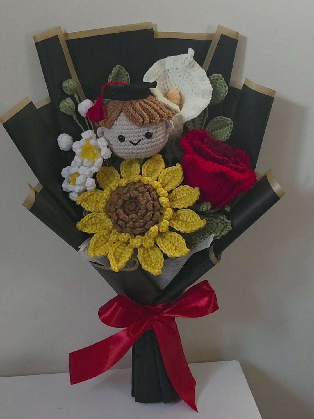 Graduation bouquet made of crochet flowers, and a small figurine on a white background