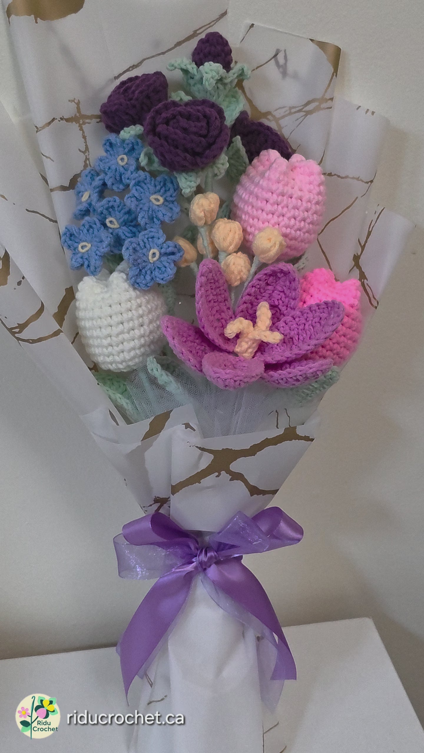 A crochet flower bouquet with charming blend of purple roses, blue blossoms, and soft pastel tulips