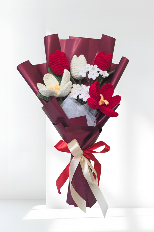 Bouquet of knitted flowers in red, white, and yellow with ribbons on a white background