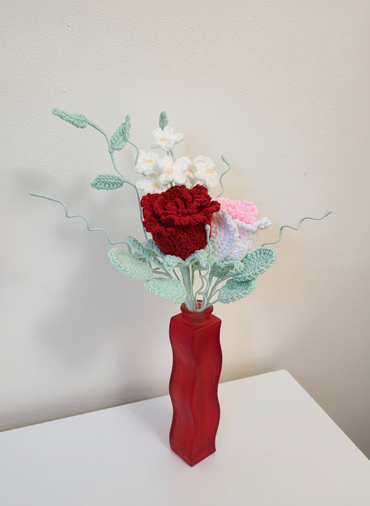 Decorative flower arrangement in a red vase on a white surface with a light gray background