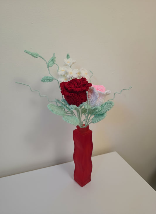 Decorative flower arrangement in a red vase on a white surface with a light gray background